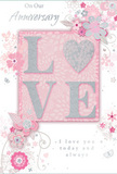 This anniversary card carries a soft, dreamy elegance that would sit beautifully beside a vase of fresh flowers on a Nunhead kitchen table. At the core of the design, the word "LOVE" is featured in raised, solid letters, creating a subtle three-dimensional effect that adds weight and importance. Each letter is trimmed with fine glitter in gentle blush and pearlescent tones, forming a delicate, sparkling border that catches the light as you tilt the card, much like sunlight glinting off petals arranged in a jug by a local florist. The interior of the letters is smoother and more matte, enhancing the tactile contrast for anyone running a finger over the card. The background offers a wash of soft, pastel pink-calm, even, and romantic. Radiating out from around the central word is an illustrated garland of stylised flowers, leafy stems, and curling vines. These are drawn in graceful silver and pale grey lines, with careful shading that hints at overlapping petals and the gentle curve of leaves, echoing the natural shapes seen in hand-tied anniversary bouquets carried home along Nunhead Lane. The floral elements are arranged with an airy lightness, so the card never feels crowded; instead, the design breathes, like a loose, garden-style arrangement allowed to fall naturally. Interspersed are small flourishes and tendrils that lend motion and whimsy. A heartfelt anniversary message in elegant script is tucked thoughtfully within the design, complementing the art without overpowering it. Altogether, the card feels like a quiet tribute to enduring love, perfectly in tune with the intimate, neighbourly character of Nunhead and ready to accompany same-day flower deliveries for special milestones.